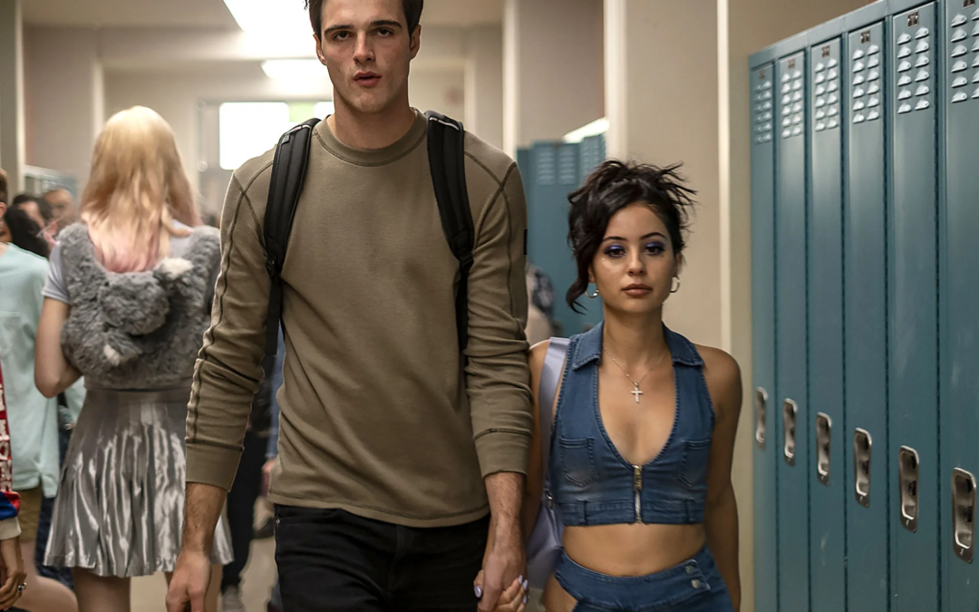 A tall male and shorter female walk down a hallway lined with lockers.